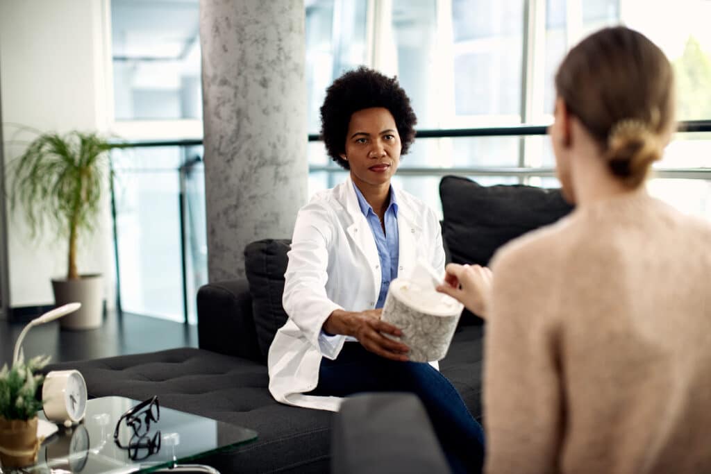What is Ibogaine? 4 Black female psychotherapist giving tissues to a patient during an appointment at her office.