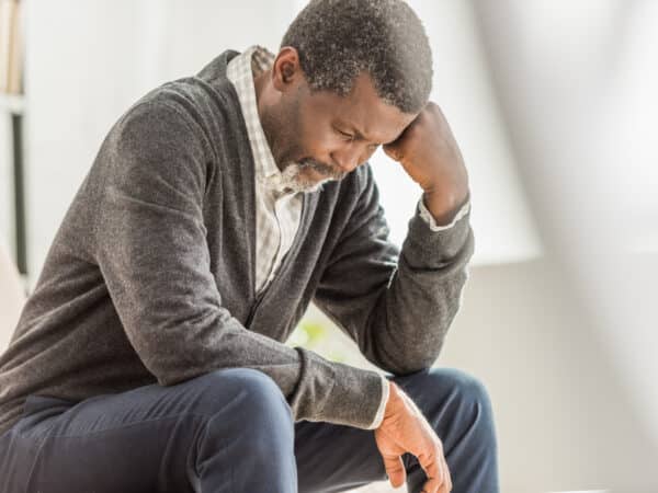 selective focus of depressed african american man sitting with bowed head